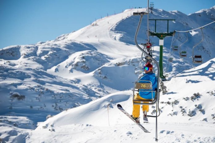 Skiër op een skilift tussen besneeuwde bergen in Slovenië