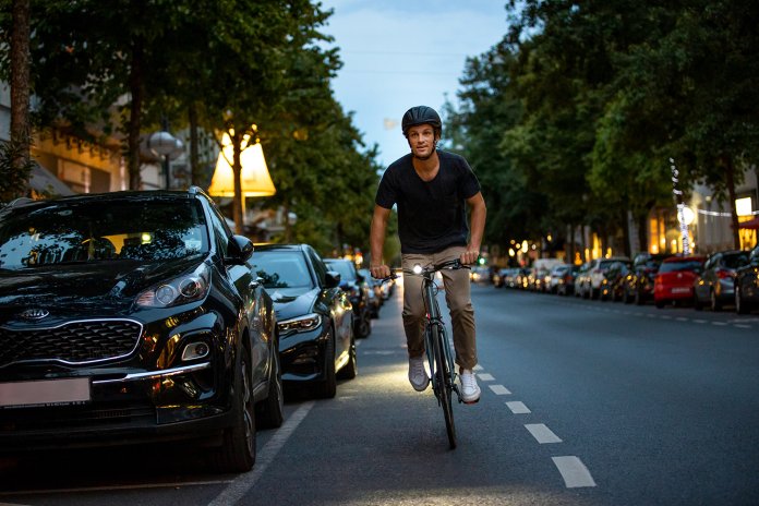 Fietser in de duisternis op de openbare weg met helm en fietsverlichting