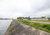 Twee fietsers met fluohesjes op een jaagpad langs een kanaal.